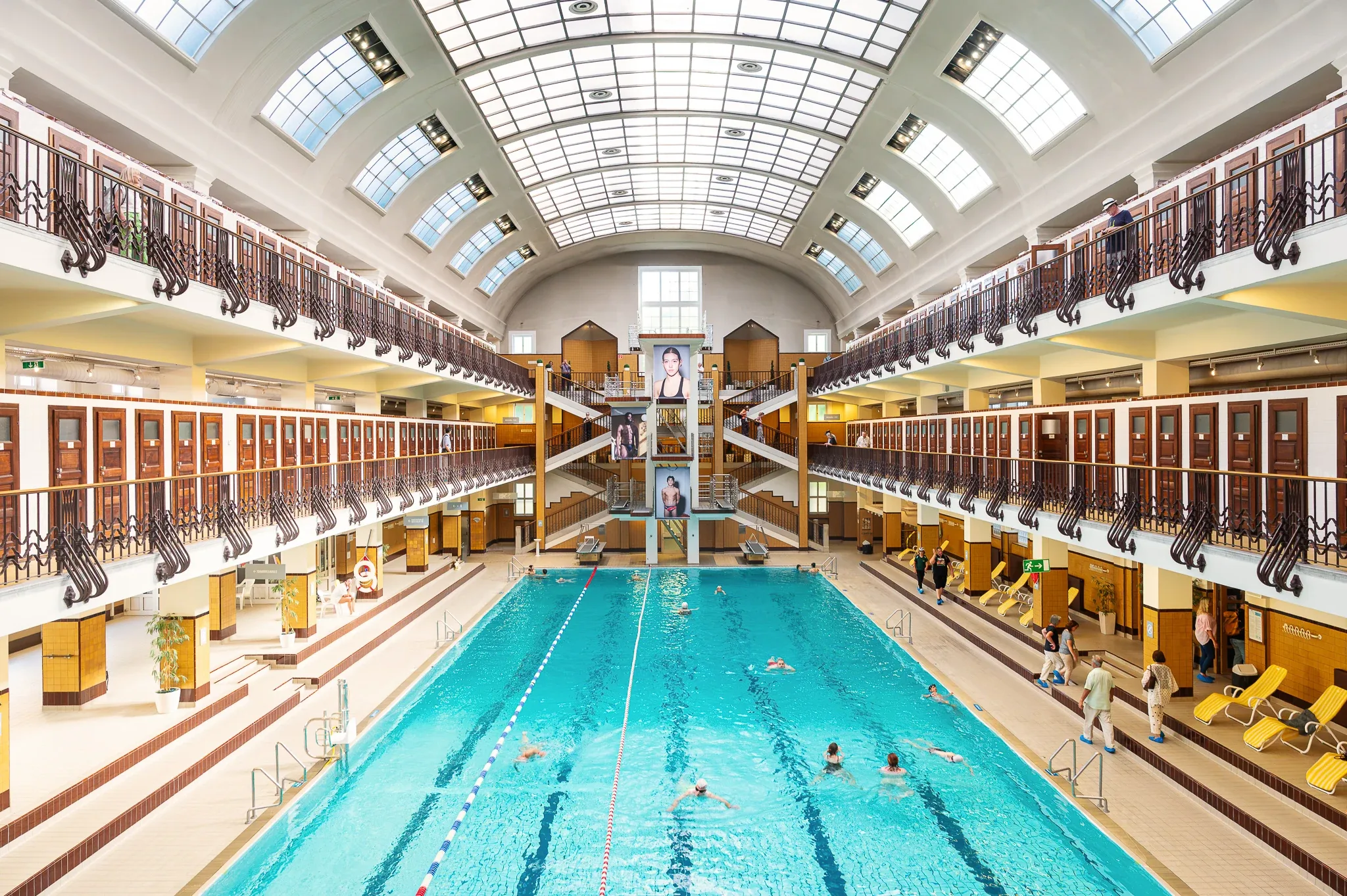 Wiener Amalienbad: Innenaufnahme der historischen Schwimmhalle mit türkisem Wasser und Kabinengalerien.