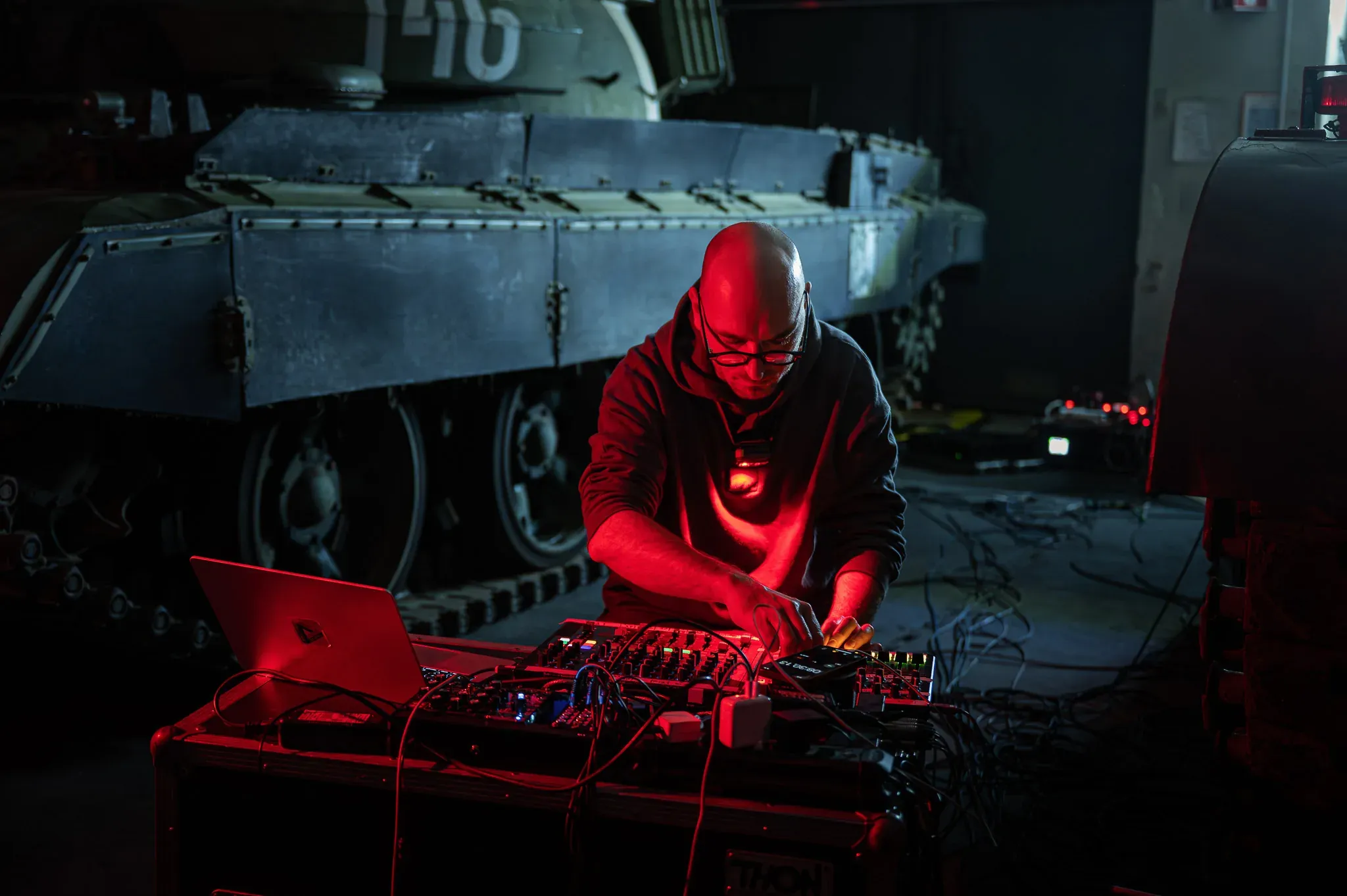 DJ im roten Licht vor einer großen Skulptur.