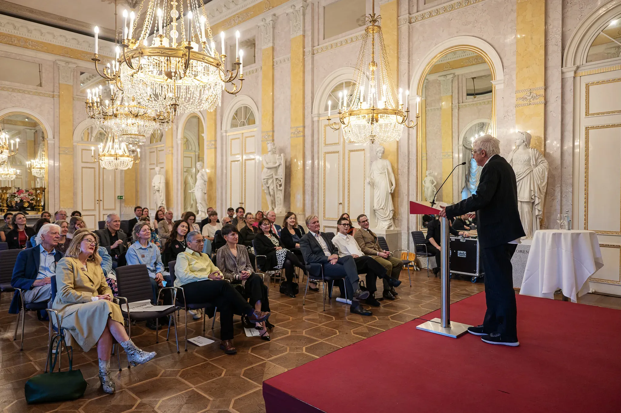 Vortrag im historischen Festsaal, Publikum in Stuhlreihen.
