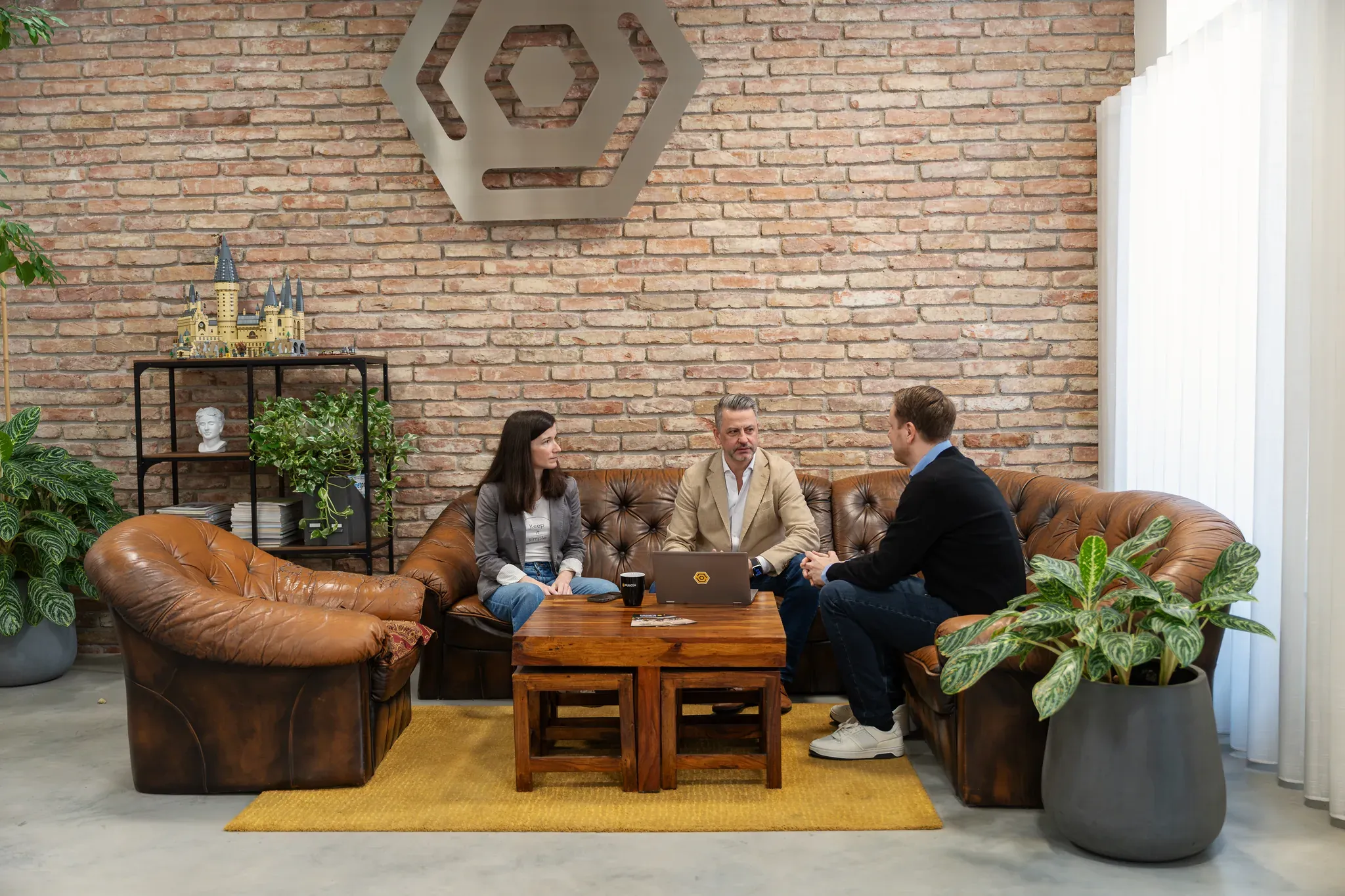 Besprechungsecke im Büro: Ledersofas vor einer Ziegelwand.